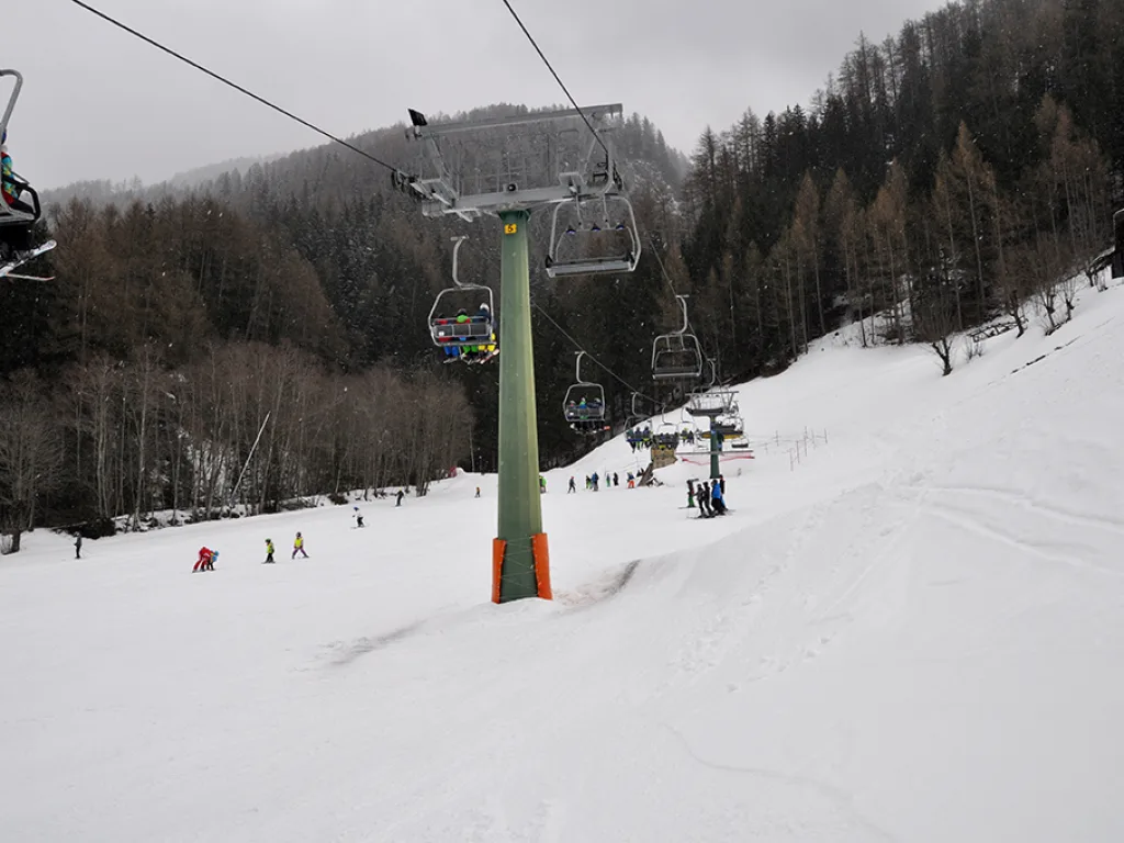 Sessellift über einer teilweise aperen Piste.